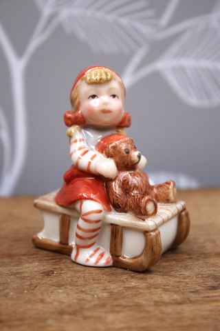 Royal Copenhagen Pixie in porcelain, no.764. Girl on a sled with a small teddy bear.