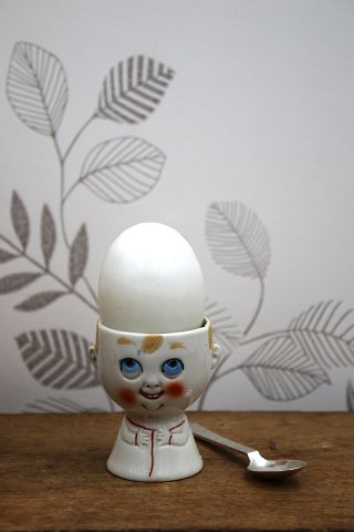 Old egg cup from the 1930s in porcelain with a painted funny face.